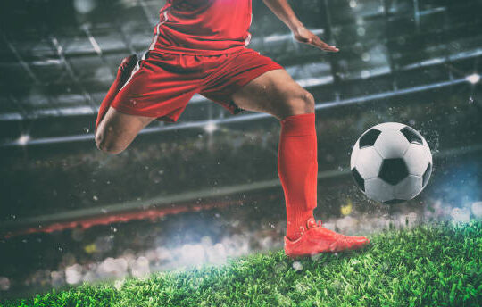 Soccer player kicks the ball vigorously at the stadium