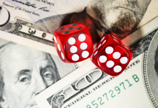 Two red dices on an American one hundred dollar bill.