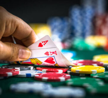 Gambling Hand Holding Poker Cards and Money Coins Chips